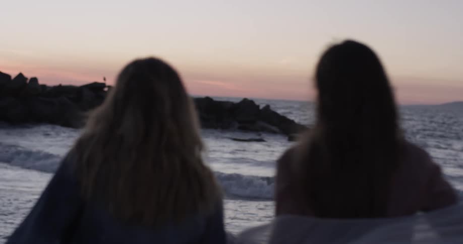 Two women dancing on the beach at sunset