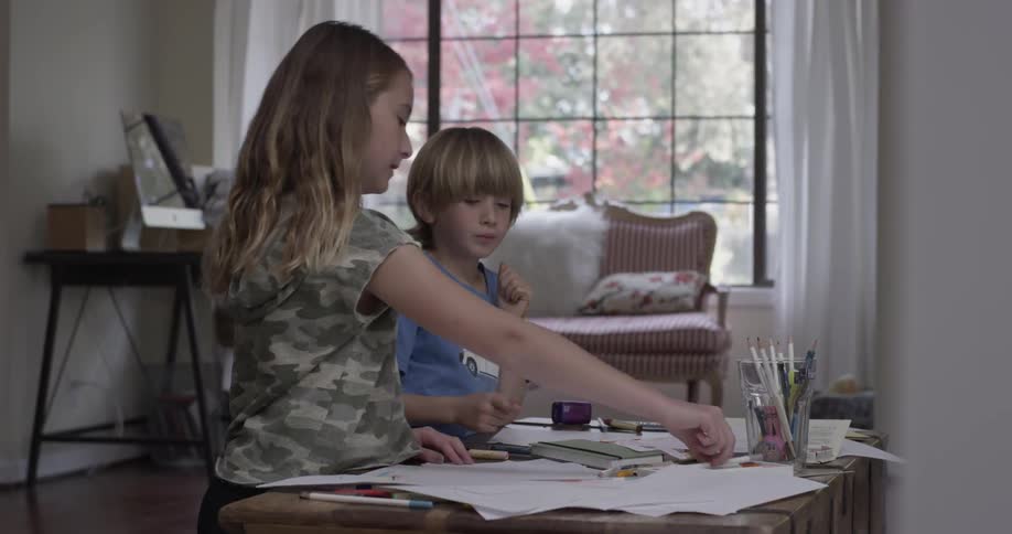 Two children draw at a small table