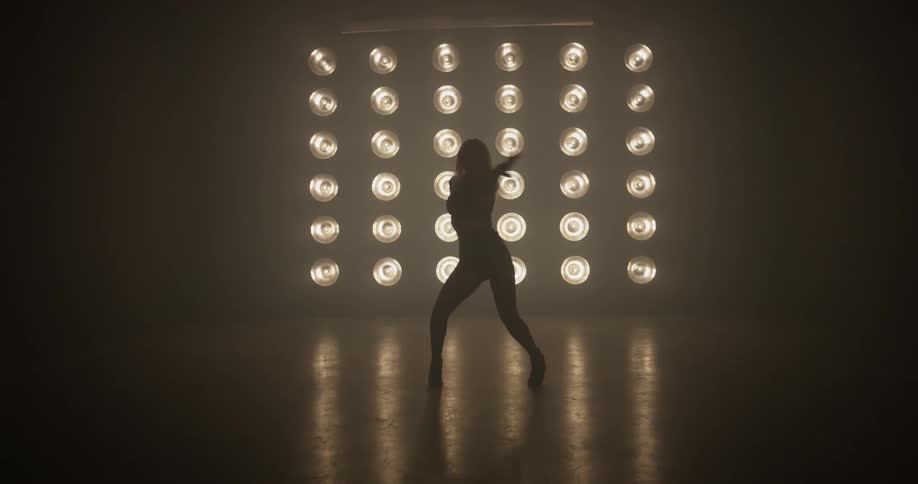 A woman is dancing in a dark room