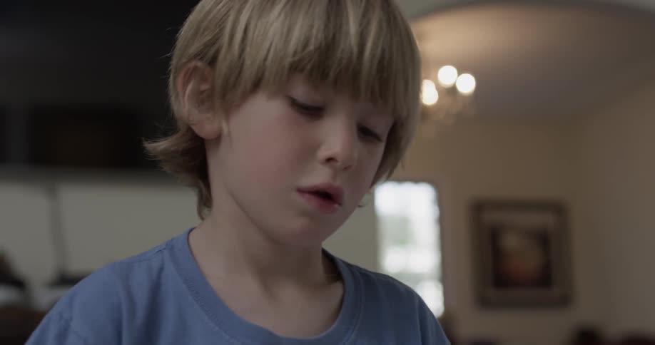 Boy intently works on a craft in a house