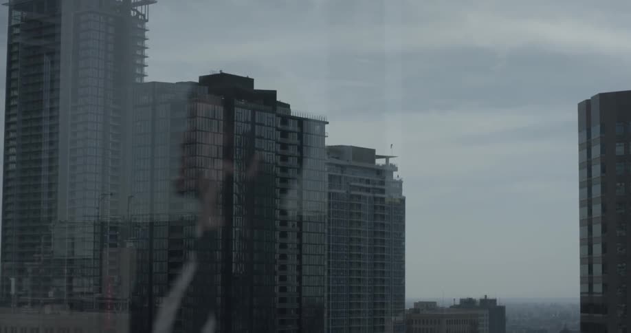 Reflection of a building while watching a man talk on a phone through glass