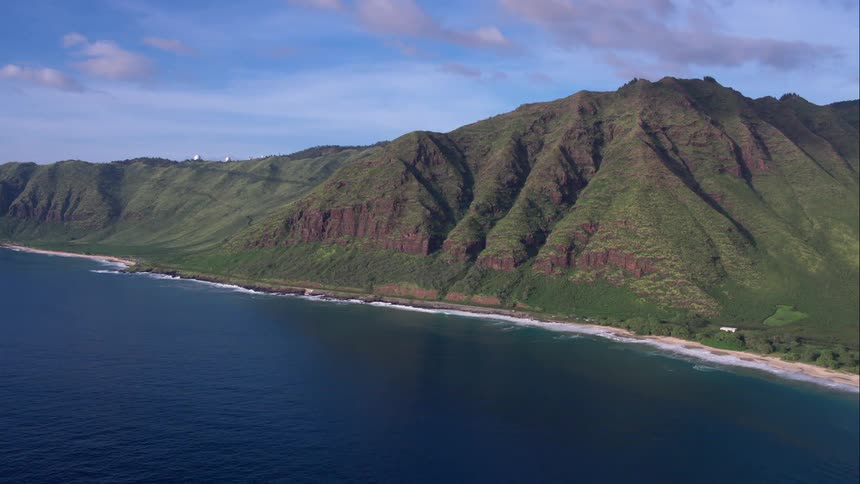 Green hills by a bright blue ocean