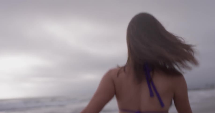 Woman jumps and turns around walking on the beach