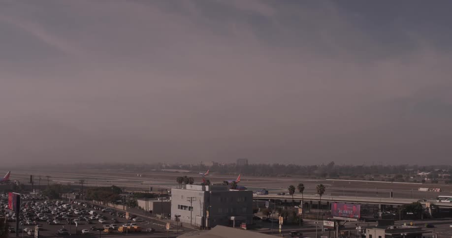 Airplanes landing at an airport surrounded by cars and parking lots