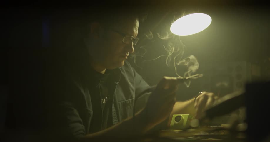 A man sits in a workshop using a tool