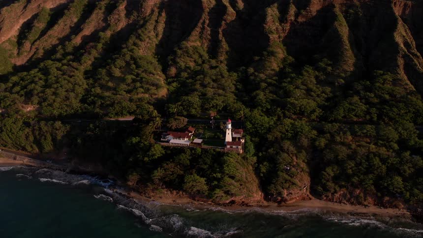 A lighthouse set into a tree lined mountain on the ocean