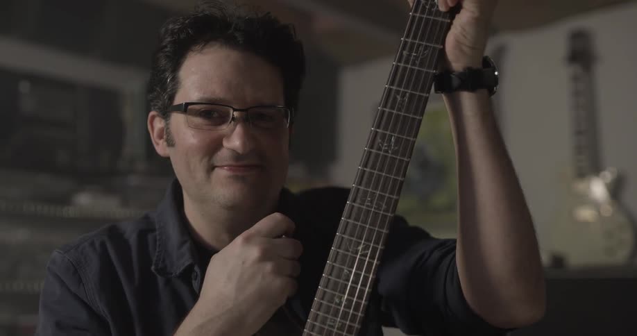 A man picks up a guitar and strums the strings