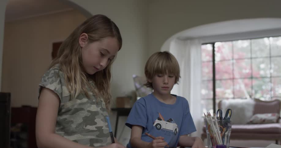 Two kids playing at a craft covered table