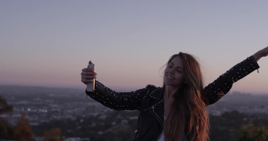 A woman is taking pictures of herself outside