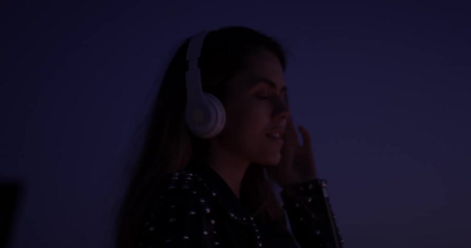 Woman wearing headphones looks at her phone at night