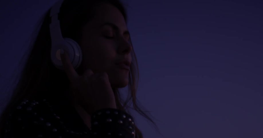 A woman is listening to music through headphones on her phone