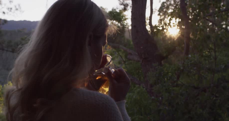 A woman is outside drinking from a glass