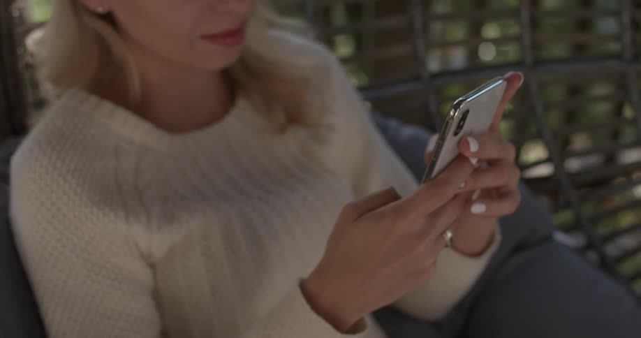 A woman is on her phone while sitting on a chair