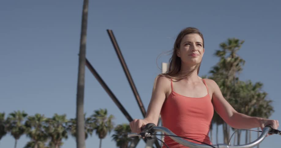 Woman smiles while riding a bike near palm trees