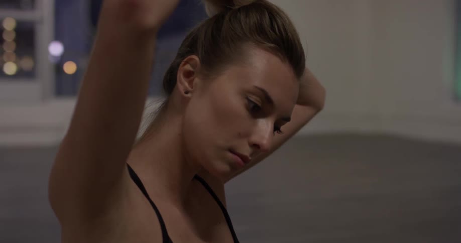 A woman brushes her hand over her bun, and removes the hair tie