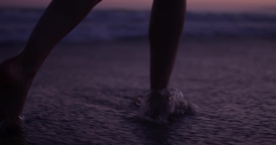 Person walking into the ocean at sunset