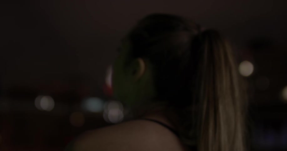 A woman turns and looks out at the city at night