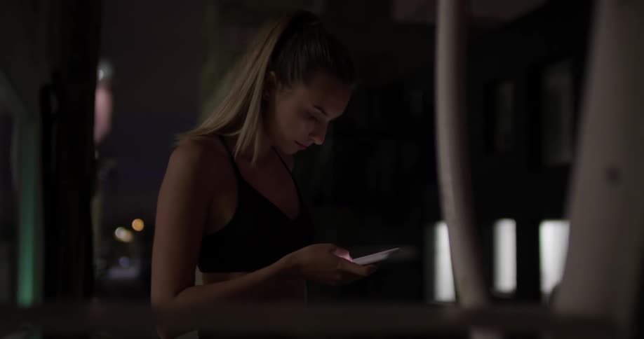 Woman scrolls on her phone in a dark room
