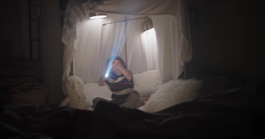 A boy is playing with a flashlight indoors