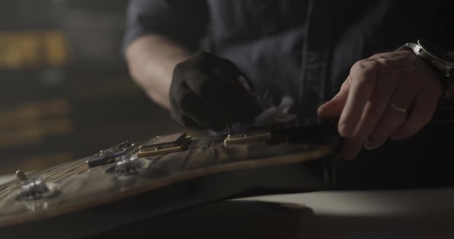 Man cleans guitar with cloth