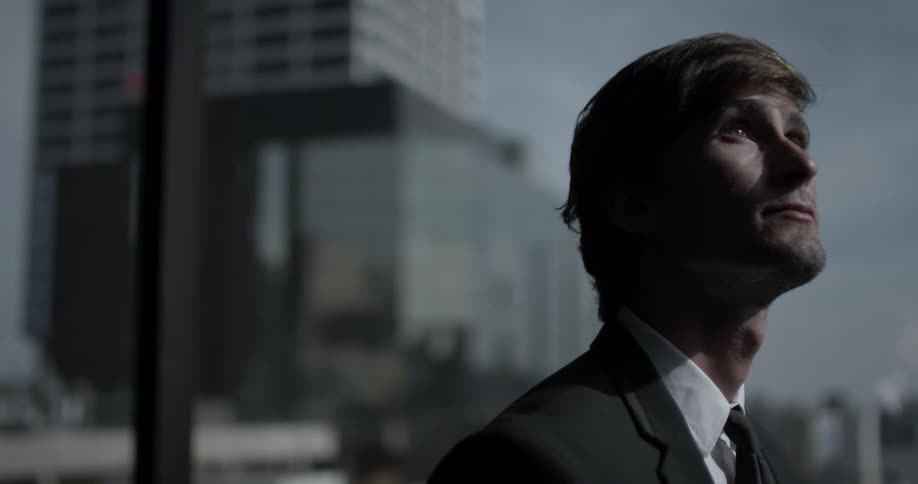 A business man looks up and out of a window