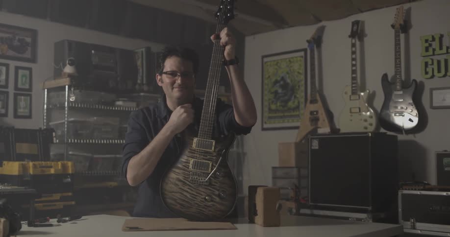 Man pick up guitar from counter and strums it