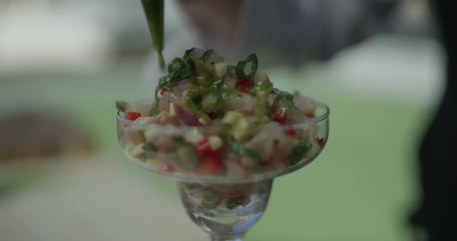 Green substance is drizzled on top of a stack of food inside a drinking cup