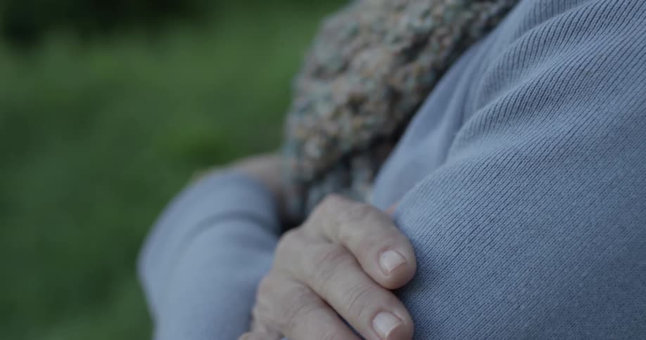 An older woman crosses her arms as she sits looking at the scenery