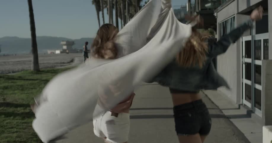 Two women dancing walking down a sidewalk