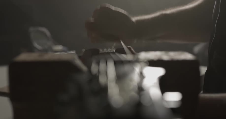 A man stretches guitar strings away from a guitar's fretboard