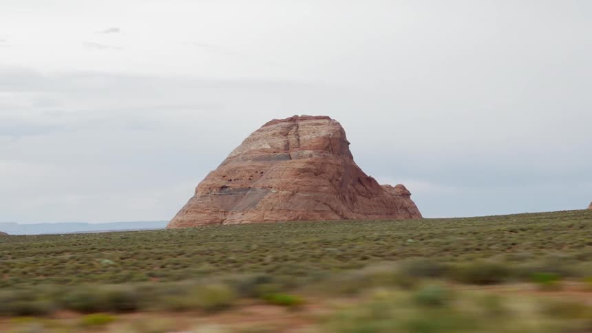 Driving through the desert, gazing at a large rock formation