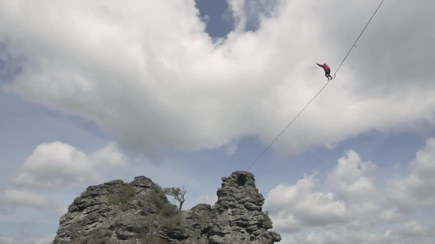 A person balancing on a tightrope between two cliffs