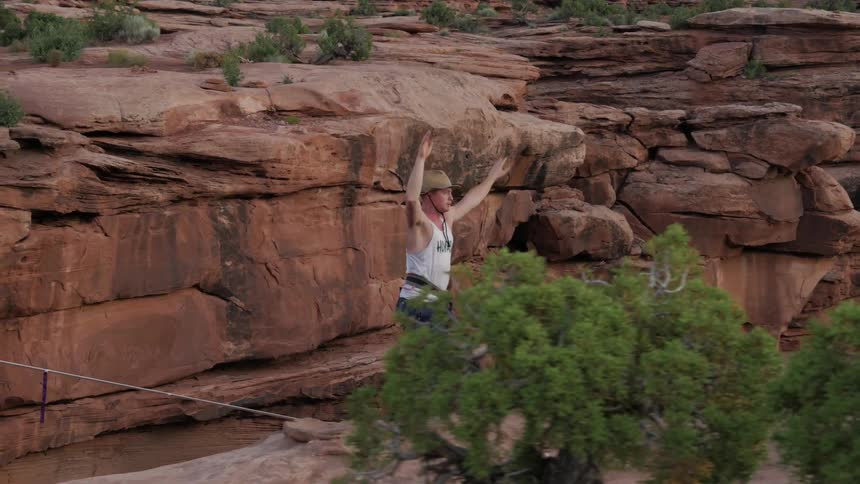 A man balancing on a tightrope in a canyon