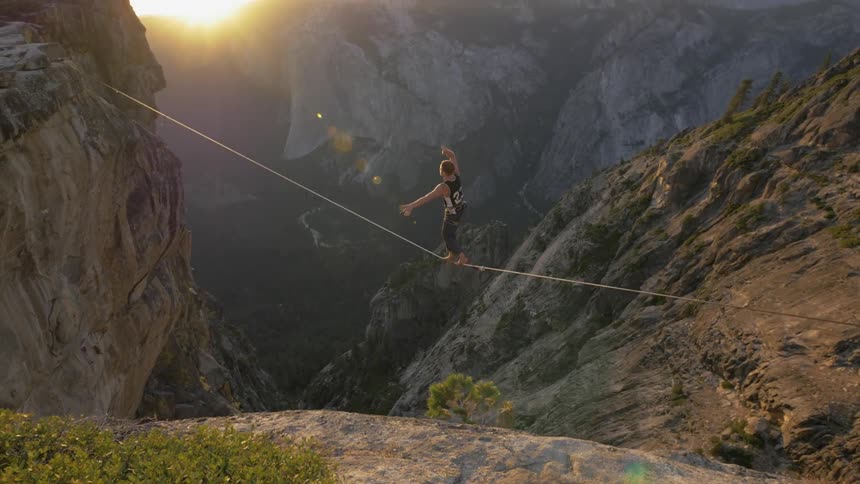 A man balancing on a tightrope in a canyon