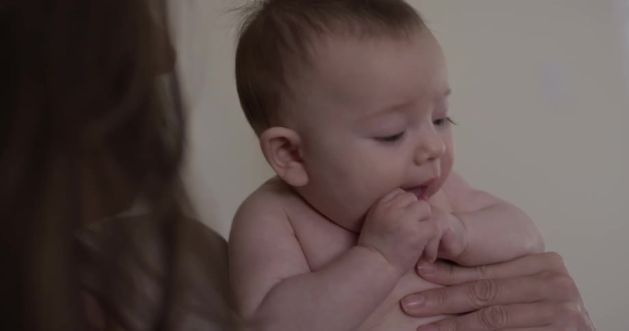 Woman holds baby who's sucking on his hand