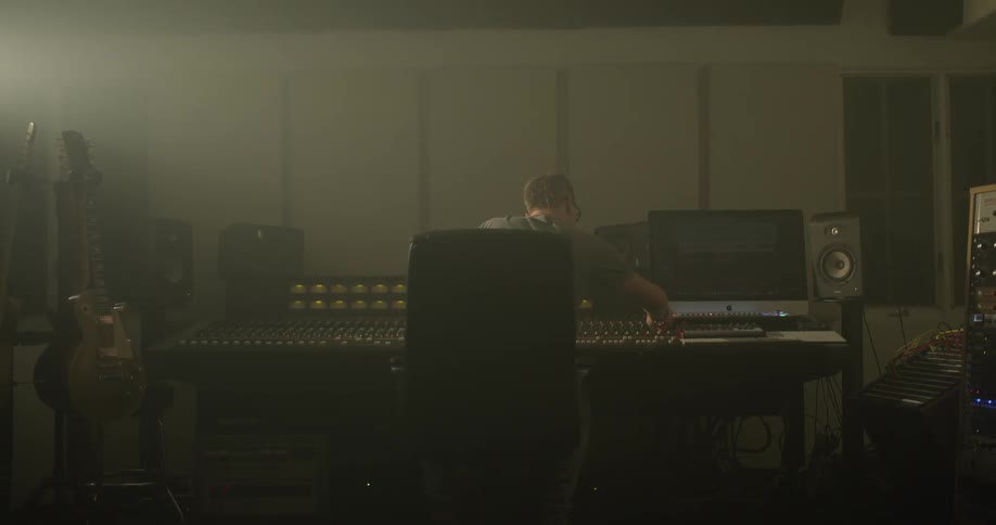 Man leans forward to adjust audio mixer settings