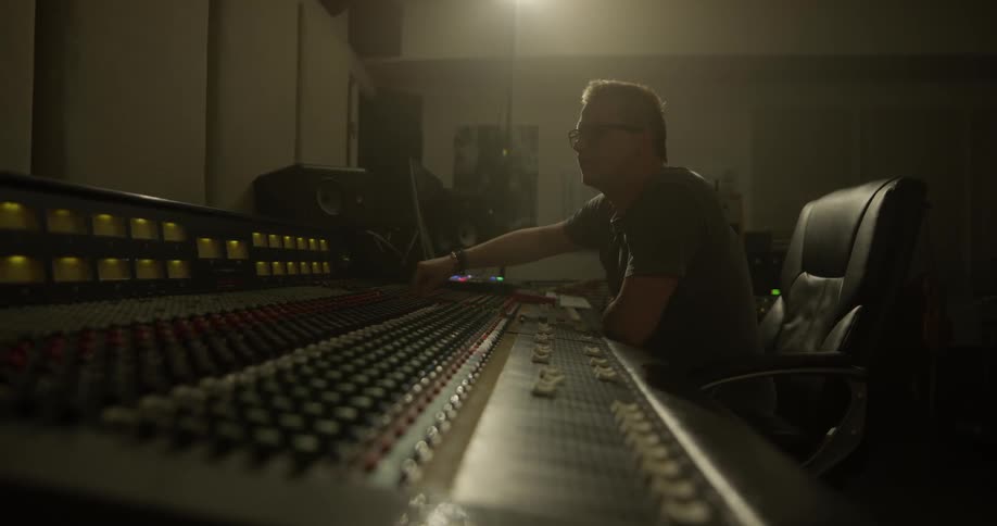 Man removes headphones and modifies audio mixer settings