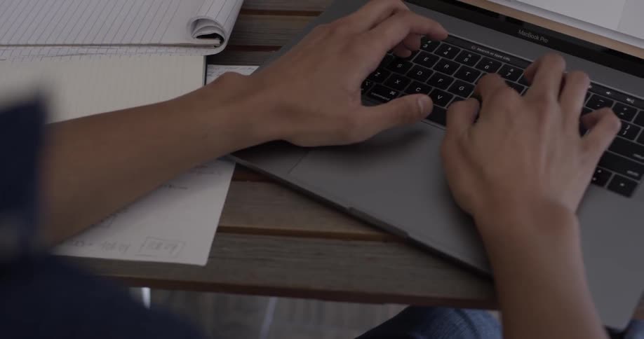 A man types something on a laptop keyboard