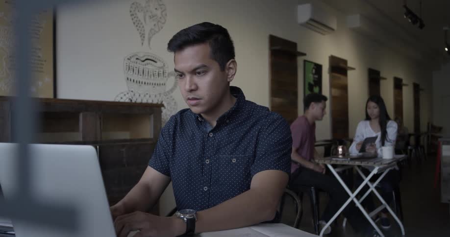 Man types on laptop computer in cafe