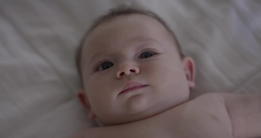 Laying baby looks up and around