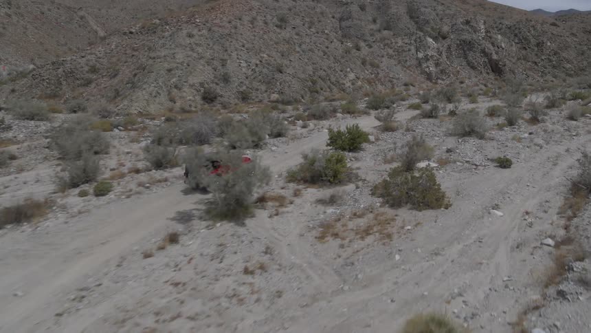 An vehicle driving over a rocky and sandy area