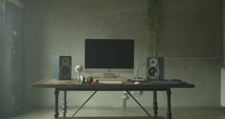 Slow motion zoom out of a desk with computer headphones and speakers