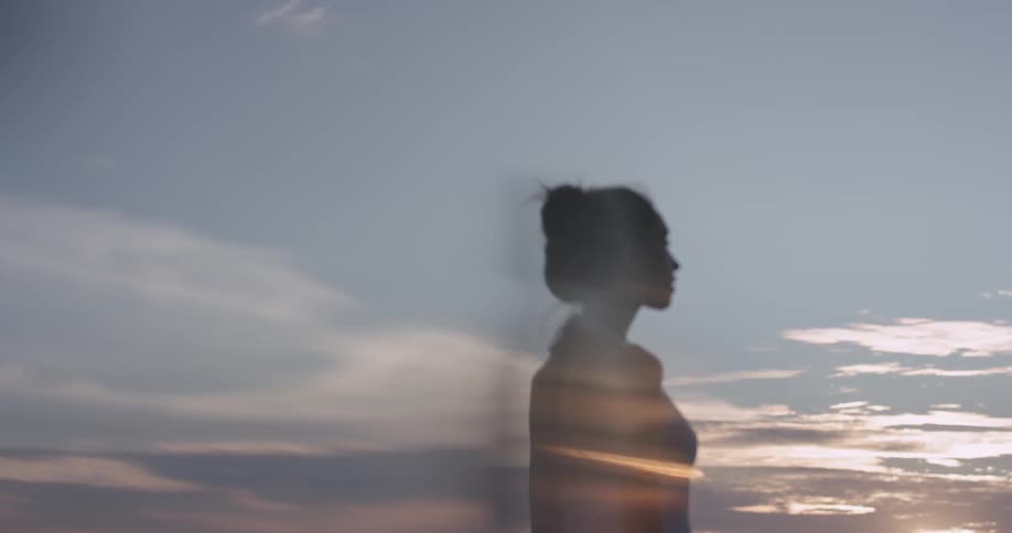 A woman stares out into the sunrise