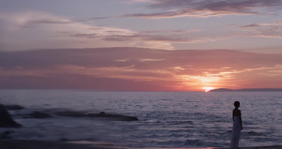 Woman standing on a beach during sunset