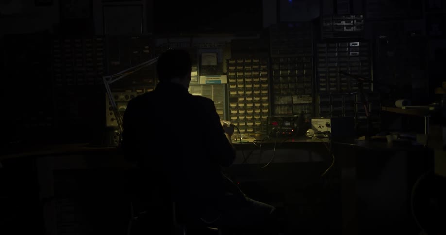 Man sits at workbench in dark light