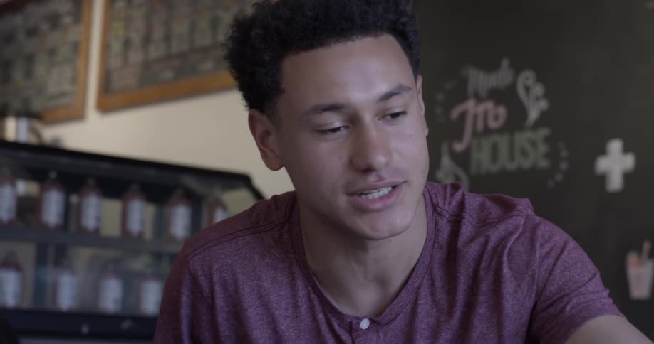 Man sits before chalkboard in restaurant talking and gesturing