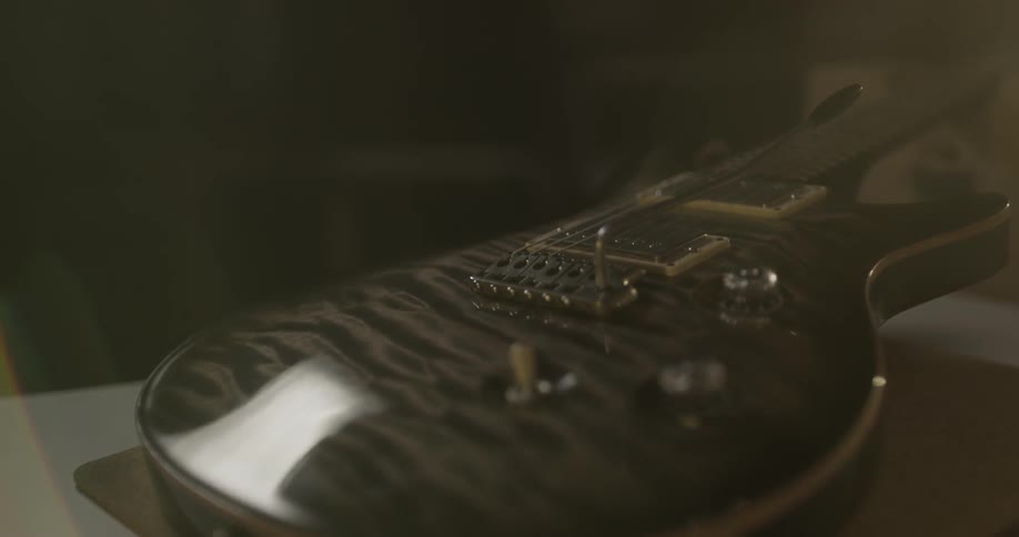 A guitar sits on a table with a light shining on it