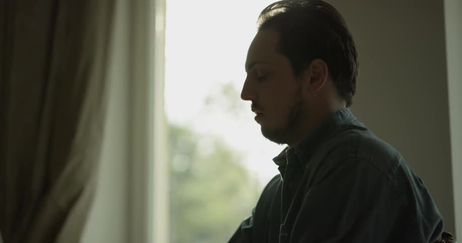 Sun filters through a window on man playing piano