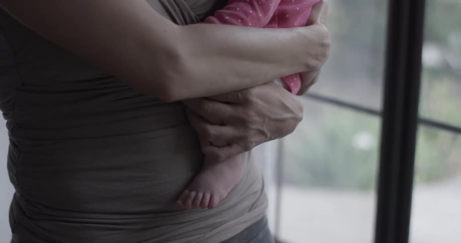 Woman holds baby near a window