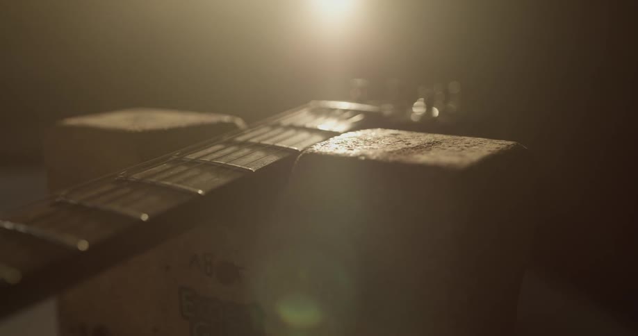 Guitar is shown in dimly lighted room laying on a wooden block